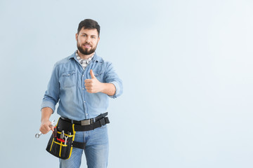 Handsome plumber showing thumb-up on color background