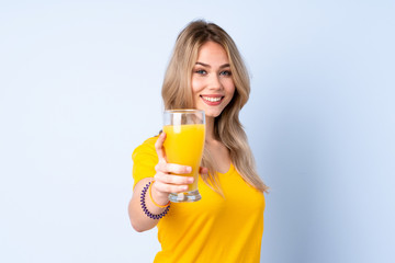 Teenager Russian girl holding an orange juice isolated on blue background with happy expression