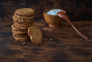 Oat cookies and flakes on a dark wooden table
