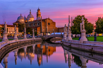 View of canal with statues on square Prato della Valle and Basilica Santa Giustina in Padova (Padua), Veneto, Italy. Sunset cityscape of Padua.
