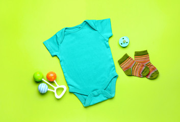 Baby clothes and accessories on color background