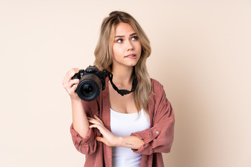 Young photographer girl over isolated background with confuse face expression