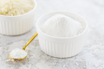 Rice flour on a background of white rice on a gray table. Gluten free, healthy diet concept.