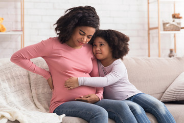 Caring little daughter comforting pregnant mom that suffering from prenatal contractions