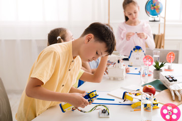 Concentrated teen boy constructing robot at class