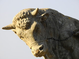 Vintage bull sculpture head isolated on pale sky background