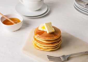 Tasty pancakes with honey and butter on table