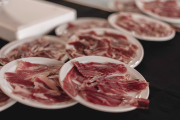 Serrano ham dishes. Typical and delicious spanish food. Close-up and selective focus in black background.