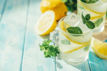 Lemonade and ingredients on blue wood background, copy space