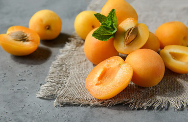 apricots with mint on a gray background, whole and half orange berries