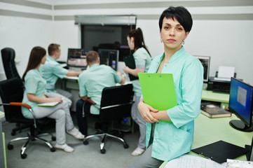 Medical theme .Portrait of female doctor with clipboard against group of doctors meeting in the mri office at diagnostic center in hospital.