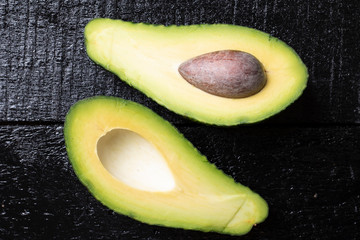 Two halves Avocado fruit on a wood background. Horizontal composition, top view