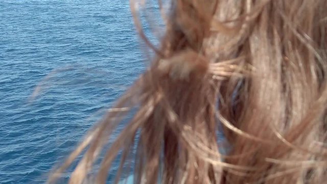 Beautiful girls brown hairs waving in the adriatic sea wind. Filmed while going to vacation in Croatia from moving ferry boat.
