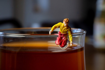Miniature guy is trying to climb out of a glass