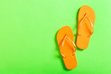 orange flip flops on green background. Top view with copy space