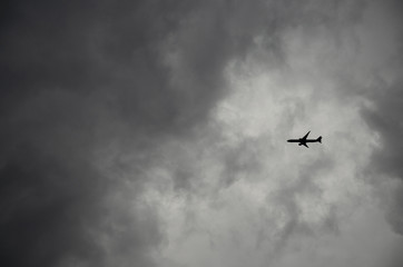 Airplane flying through dark stormy clouds in dramatic sky