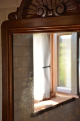 one open window reflected in an old wooden mirror