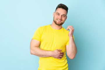 Russian handsome man isolated on blue background laughing