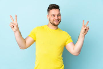 Russian handsome man isolated on blue background showing victory sign with both hands
