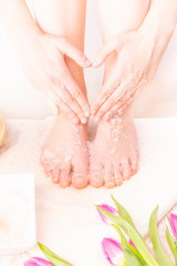 Woman doing foot peeling and making hand heart gesture. Pedicure SPA.