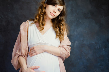 Fototapeta na wymiar Portrait of beautiful elegant caucasian pregnant young woman on dark background. Maternity fashion, femininity, pregnancy concept.