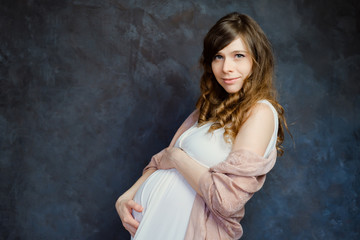 Fototapeta premium Expectant mother on dark background. Maternity fashion, femininity, pregnancy concept.
