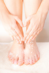 Woman doing foot peeling and making hand heart gesture. Home SPA.