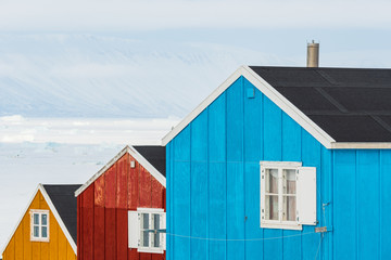 Row of colourful wooden houses against a landscape of snow drifts