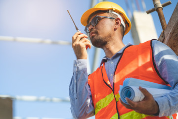 Asian engineer using radio to command to labour team in site construction.