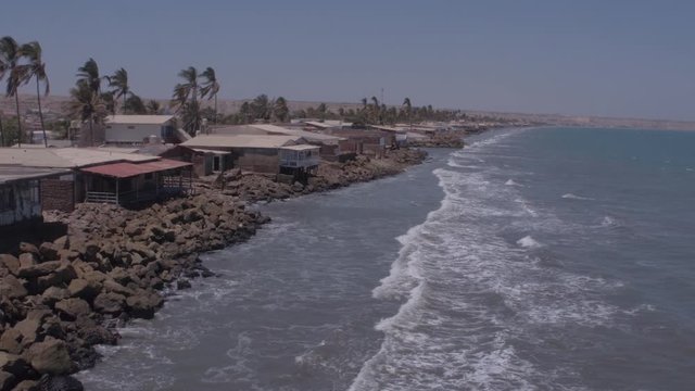 Approaching aerial drone view move of houses on Colan Beach at a sunny day in Piura Region, Peru