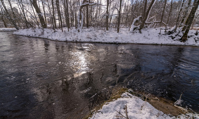 Obraz na płótnie Canvas winter landscape with wild fast flowing river, snow covered land