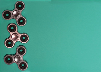 Three metal spinners are laid out horizontally on the surface, on a beautiful green background....