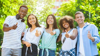 Multicultural Teen Friends Posing At Camera Outdoors And Gesturing Thumb Up