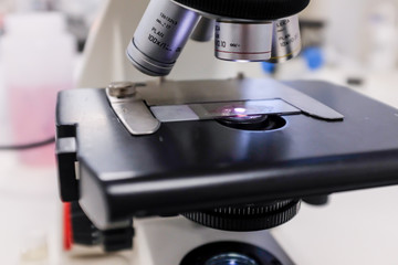 Close-up shot of microscope with metal lens at laboratory.  Chemistry and science research concept background.