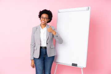 African american business woman giving a presentation on white board over isolated pink background...