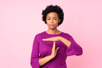 African american woman over isolated pink background making time out gesture