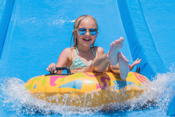 Child on water slide at aquapark. Summer holiday.