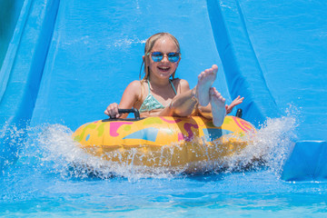 Child on water slide at aquapark. Summer holiday.