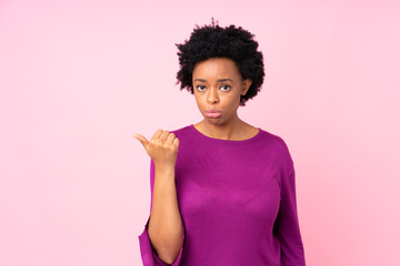 African american woman over isolated pink background unhappy and pointing to the side