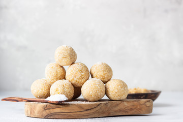 Traditional Indian festival sweets (Laddoo or Laddu) with coconut flakes on a wooden cutting board, light background, selective focus. Popular sweet snack in India.