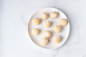 Traditional Indian festival sweets (Laddoo or Laddu) with coconut flakes on a ceramic plate, light background, selective focus. Popular tea time sweet snack in India.