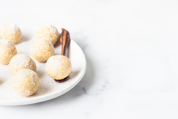 Traditional Indian festival sweets (Laddoo or Laddu) with coconut flakes on a ceramic plate, light background, selective focus. Popular tea time sweet snack in India.