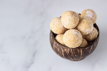 Healthy vegetarian balls with chickpea, peanut butter and coconut in the wooden bowl. Light grey background, selective focus.