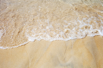 Fototapeta na wymiar Soft sea waves on sunny sandy beach top view