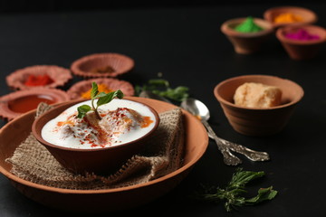 Fototapeta na wymiar Dahi vada (Deep fried balls served with curd), thandai are well known indian Holi snack. (Holi Concept)