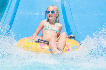 Child on water slide at aquapark. Summer holiday.