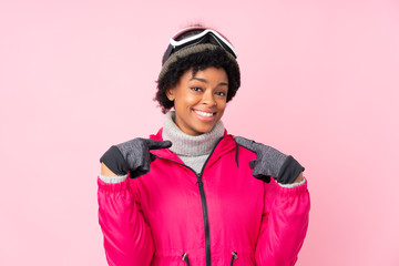 African american skier woman with snowboarding glasses over isolated pink background proud and self-satisfied