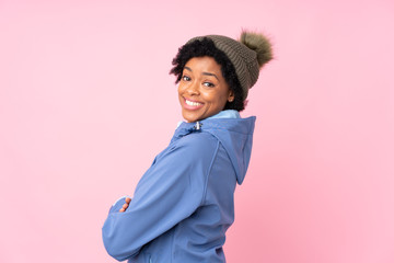 Obraz na płótnie Canvas African american woman with winter hat over isolated pink background laughing