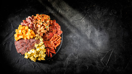 Antipasto set with gourmet food on black table top view. Mixed delicatessen of cheese and meat...