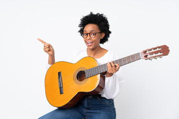 African american woman with guitar over isolated background surprised and pointing side